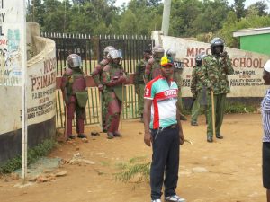 A demonstrator is blocked from accessing Migori Primary School by anti-riot police